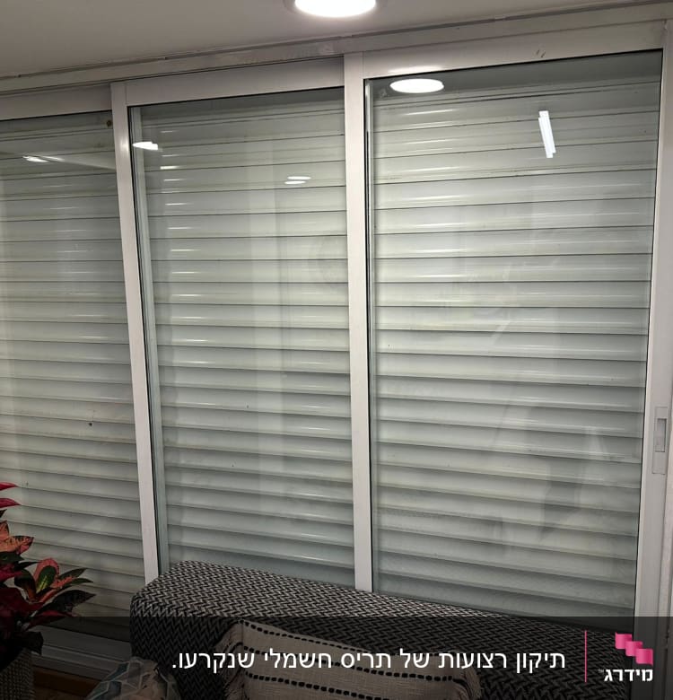 תריסים לבנים סגורים על חלון זכוכית גדול